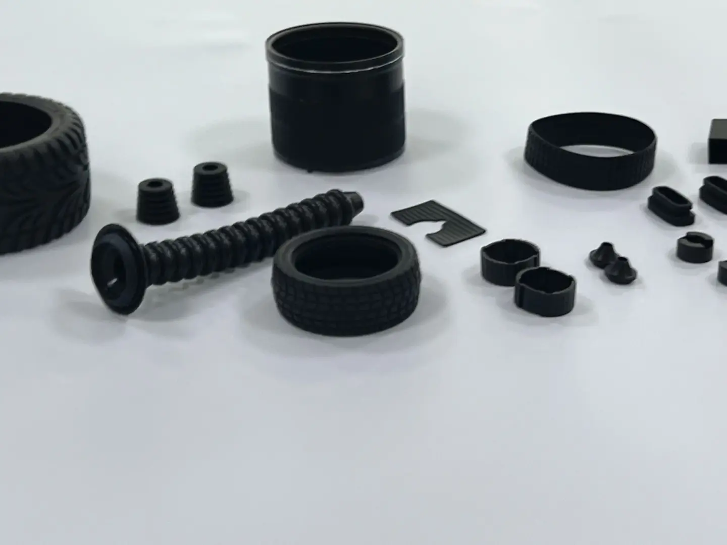 Custom molded black rubber parts collection, including boots, seals, tires and grommets for industrial equipment