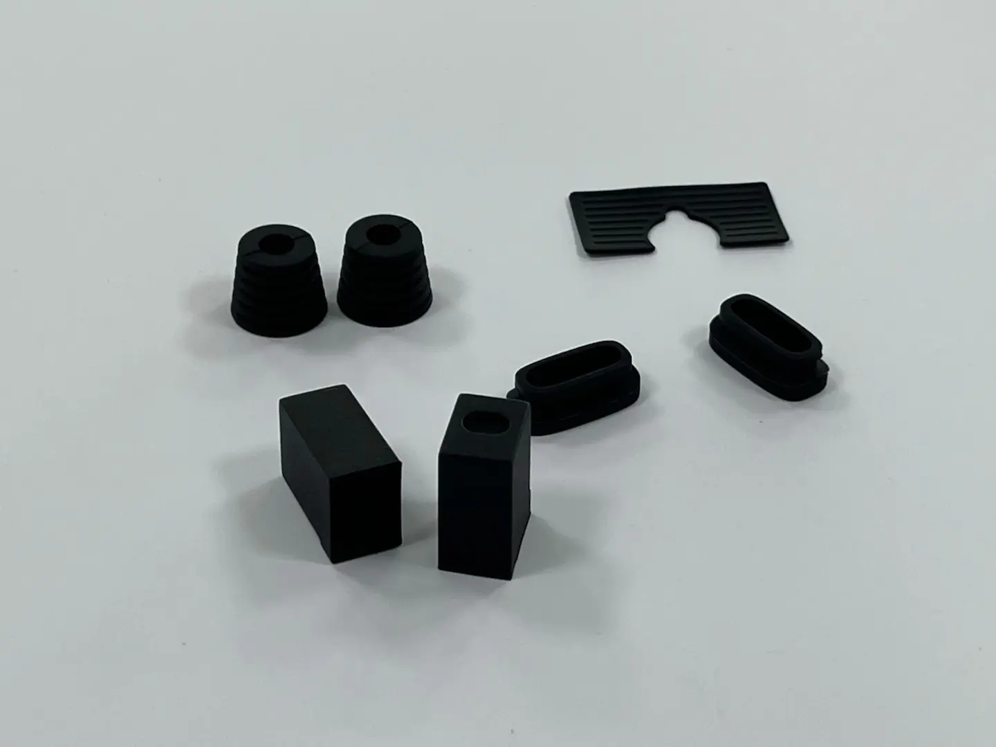 Custom molded black rubber parts collection, including grommets, bumpers, pads and protective sleeves for industrial equipment